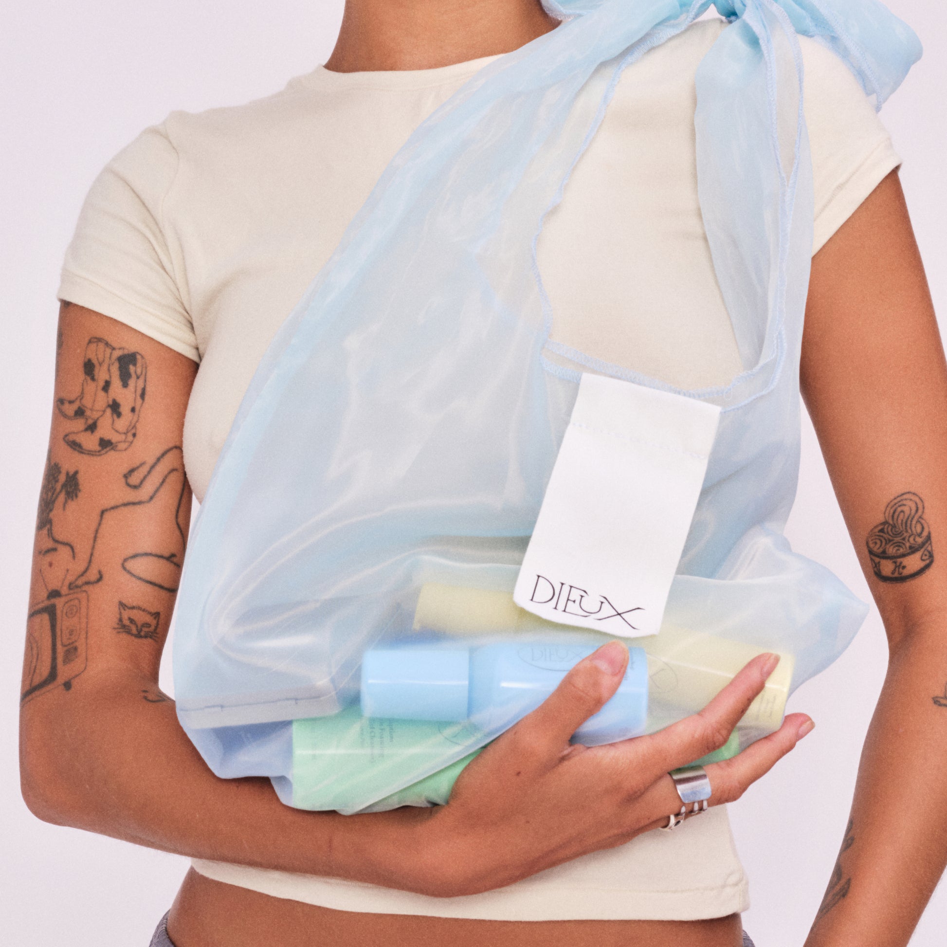Model holding The Dieux-It-All Tote, filled with Dieux skincare products.