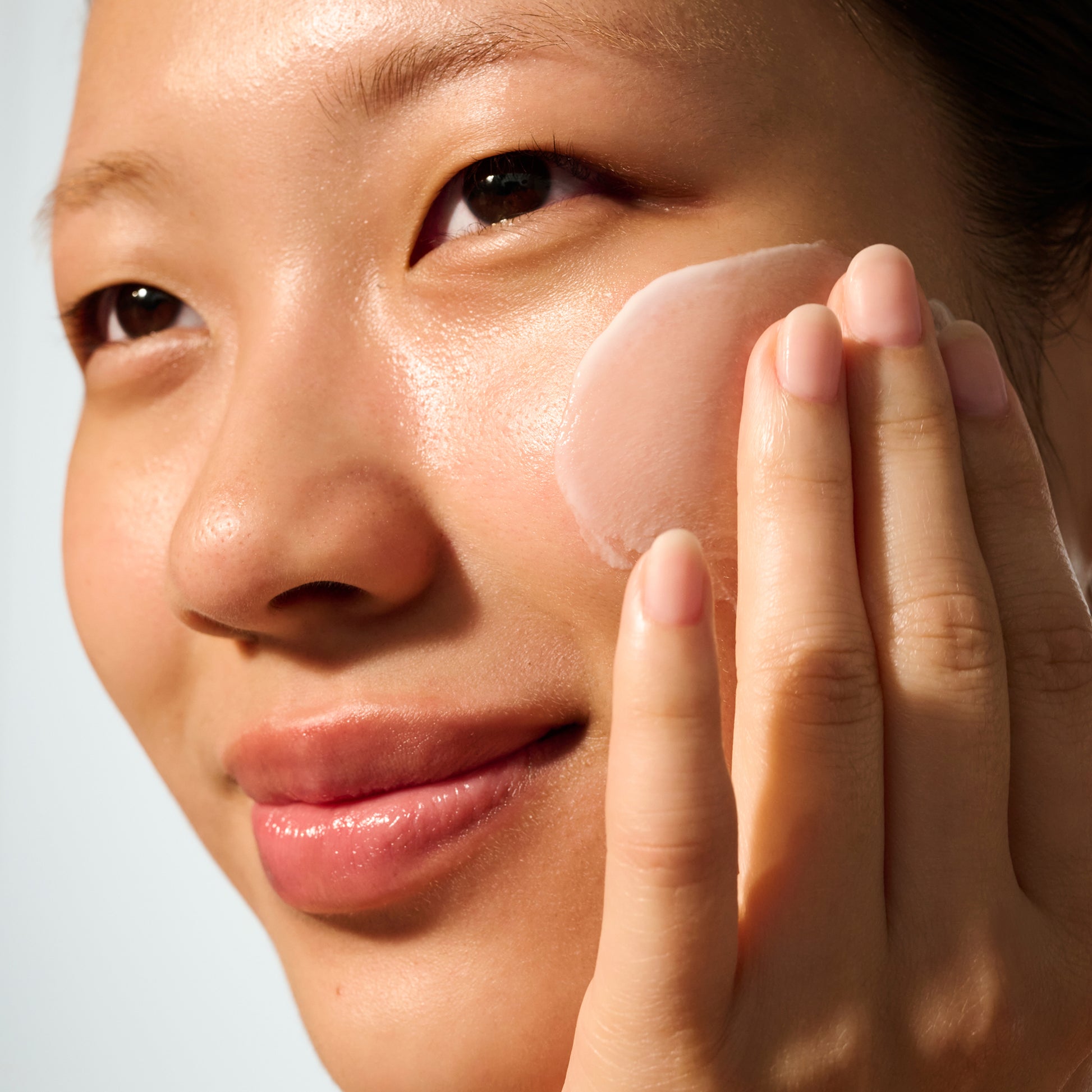 Image: Model with a swipe of Dieux Instant Angel Firming Moisturizer on her cheek.