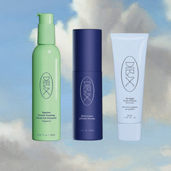 Dieux Skin products on painted cloud background: Baptism Gel Cleanser Fragrance Free, Deliverance Serum, Air Angel Gel Cream