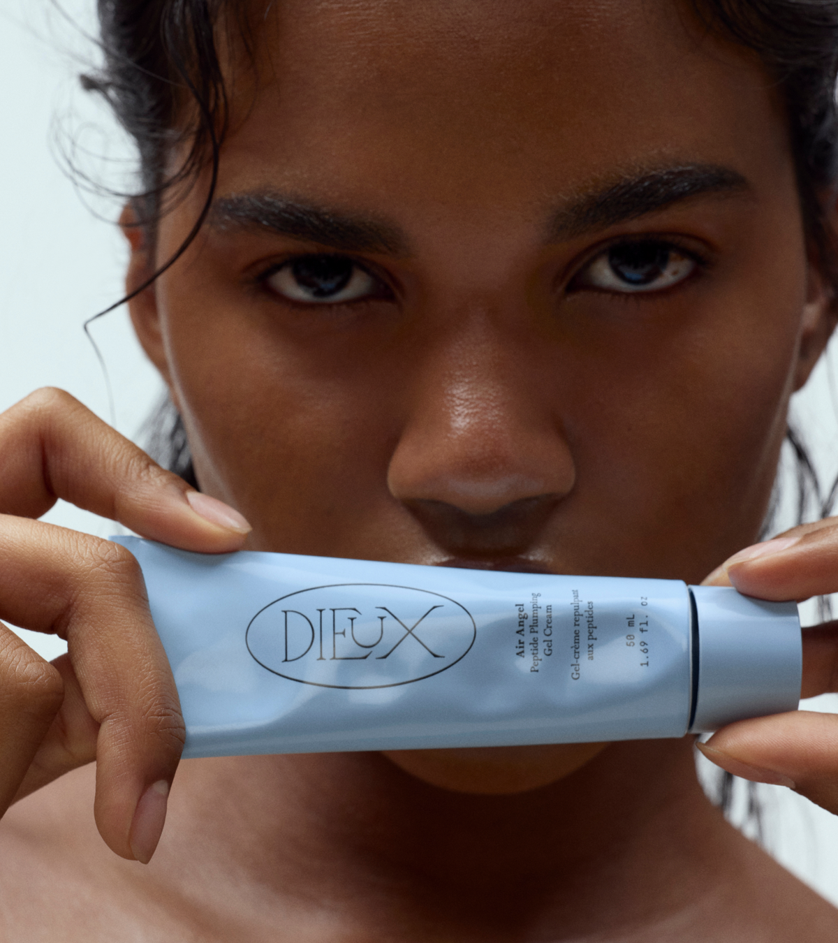 dieux Dieux-air-angel-peptide-plumping-gel-cream-squeeze-tube-held-in-front-of-mouth.